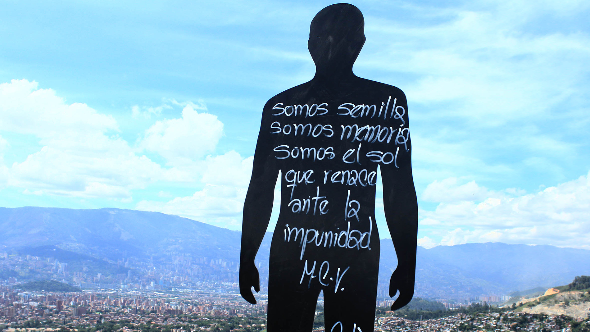 An outdoor sculpture in the form of a two-dimensional silhouette of person. It has hand-written Spanish writing on it
