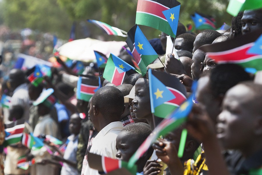 people gather holding South Sudanese flags