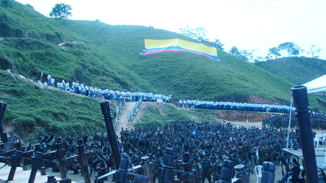 Hundreds of people gather at the bottom a green hill