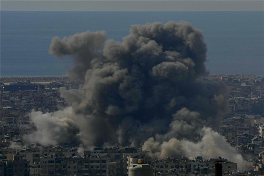 A thick cloud of smoke rises over a city skyline in daylight.