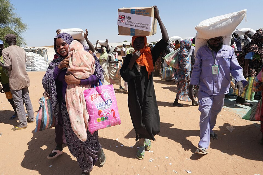 Men and women carry large boxes and sacks on their heads