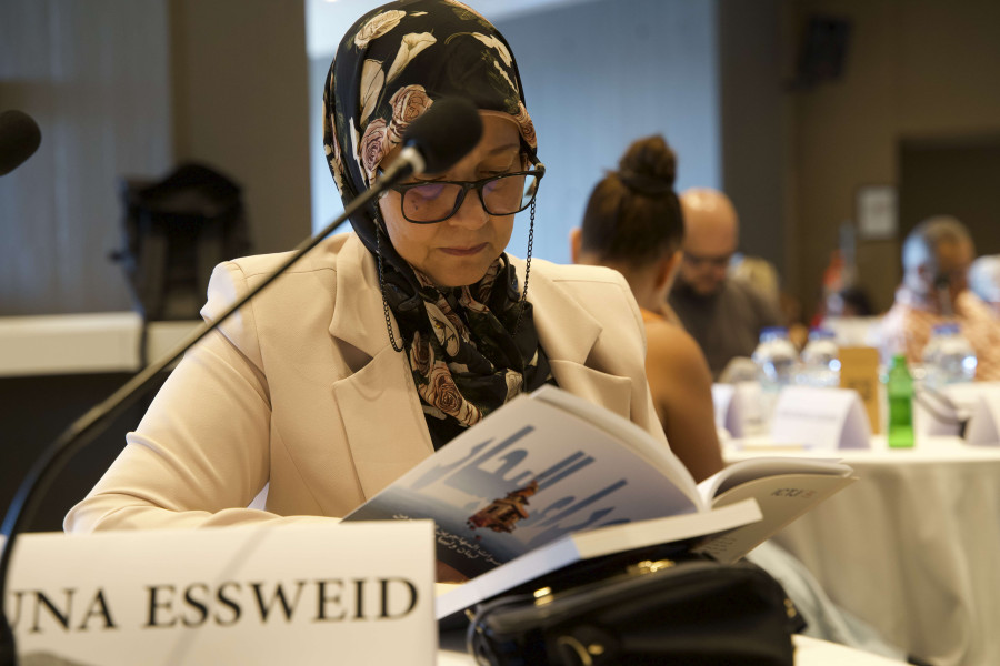 A woman seated at a table looks through a book.