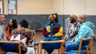 People seated in a circle speak and laugh