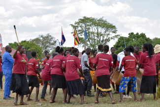 A large group of women dance in circle formation outdoors