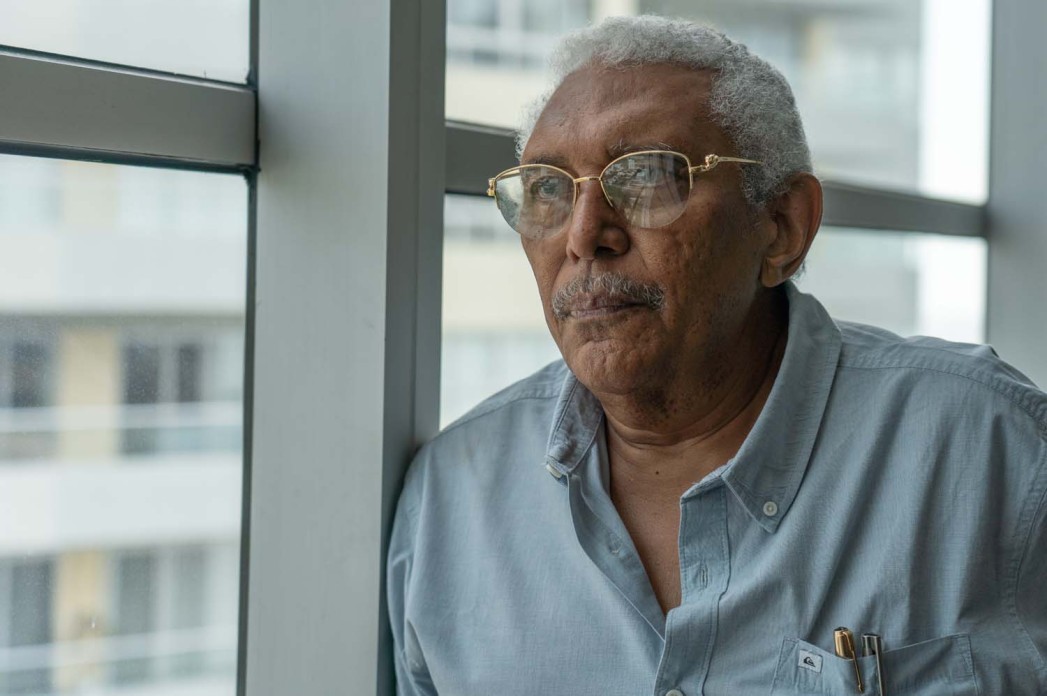 A man with glasses and a blue shirt gazes to the left of the camera