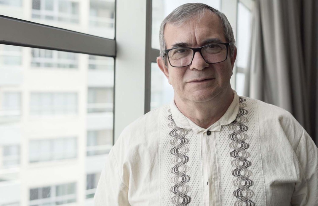A man with glasses looks at the camera
