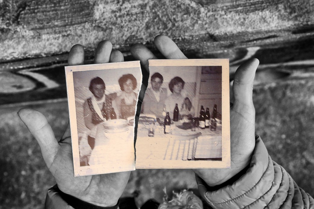 Deux mains tendues tiennent une photo de famille déchirée en deux.