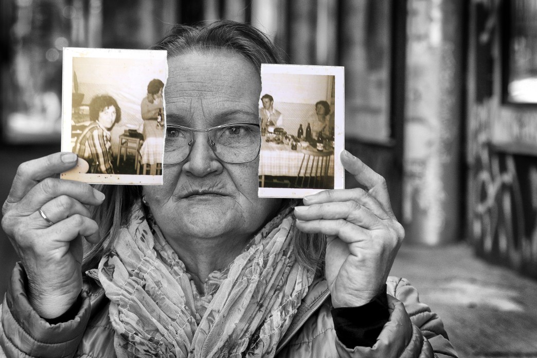 Une femme plus âgée tient une photo d'une famille qui a été déchirée en deux.