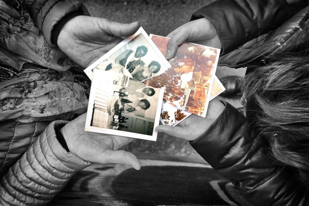 Deux paires de mains sont tendues, tenant entre elles des photos de famille déchirées en deux.