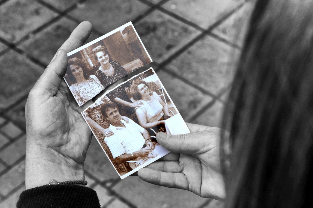 Une femme tient ensemble les deux moitiés d'une photographie déchirée.