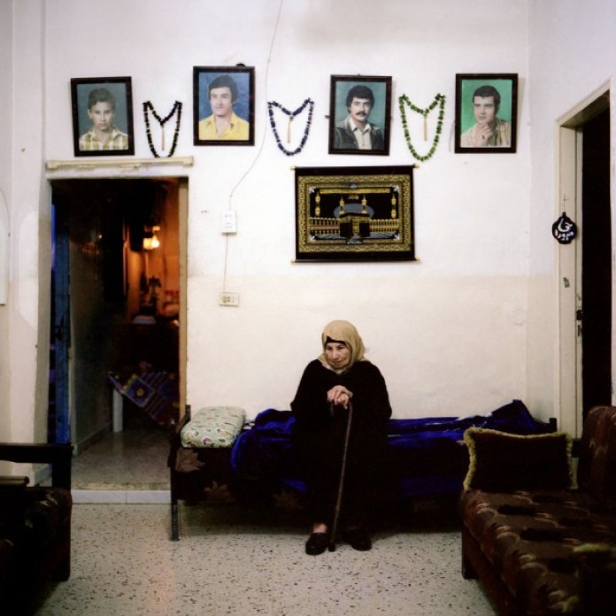 A woman alone under a set of photographs.