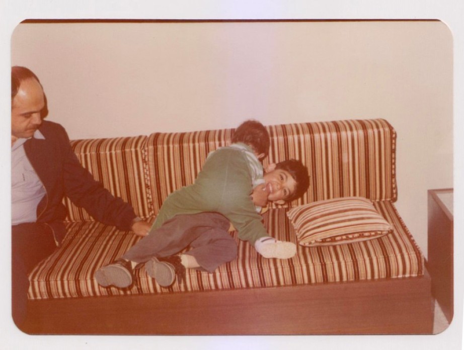 An old photo of children wrestling happily on a couch.