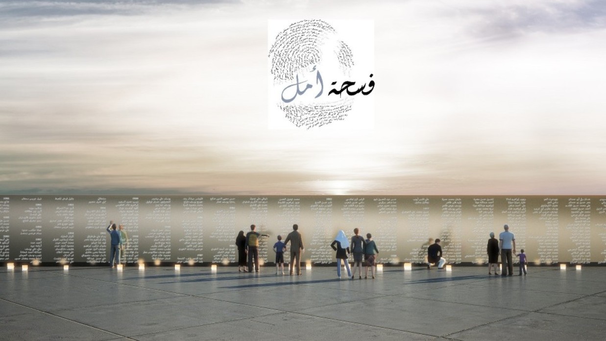 People gathered in front of a wall inscribed with text.