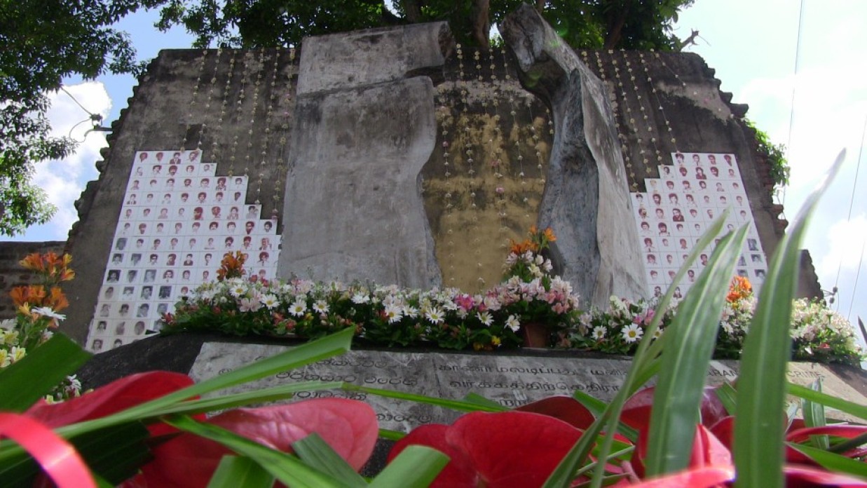 A stone monument with flowers and images of people.